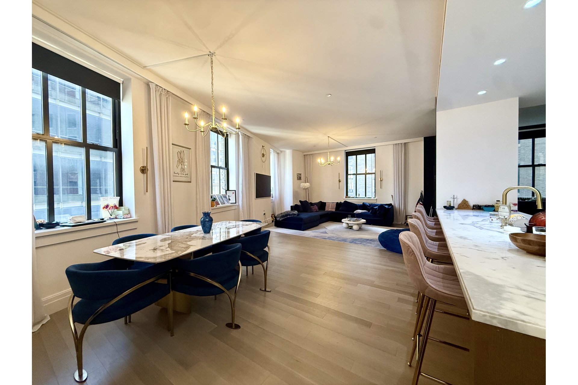 Open-plan dining and living room with a marble dining table, navy seating, and a marble kitchen island.