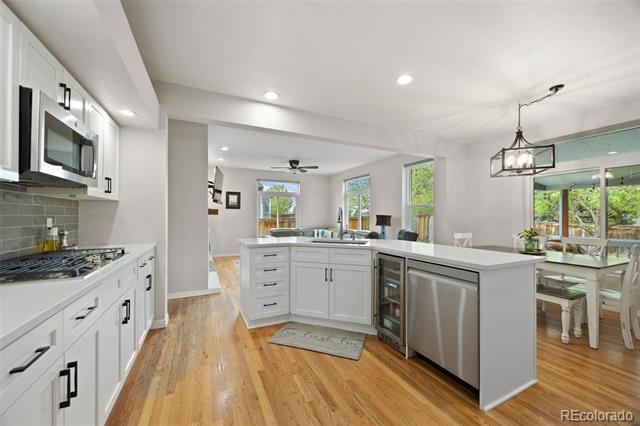 Open-plan kitchen with white cabinets, stainless steel appliances, and a large island beside a dining area.