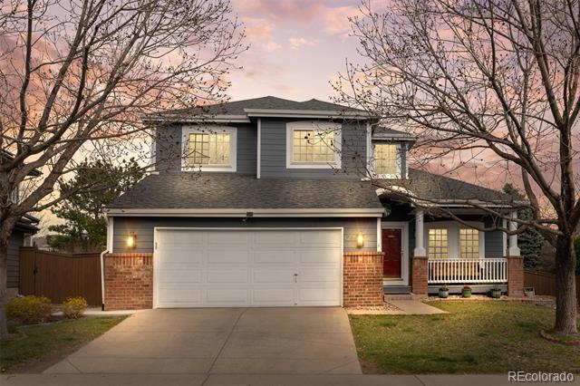 Two-story gray house with a double garage, brick accents, and a covered porch at dusk.