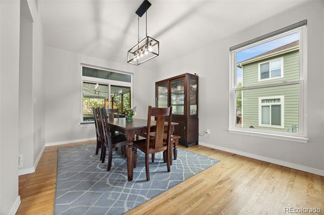 Dining room with a dark wood table, blue patterned rug, glass-front cabinet, and large windows.