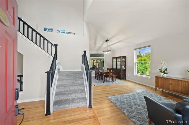 Entryway with carpeted stairs, black railings, hardwood floors, and an adjoining dining area.