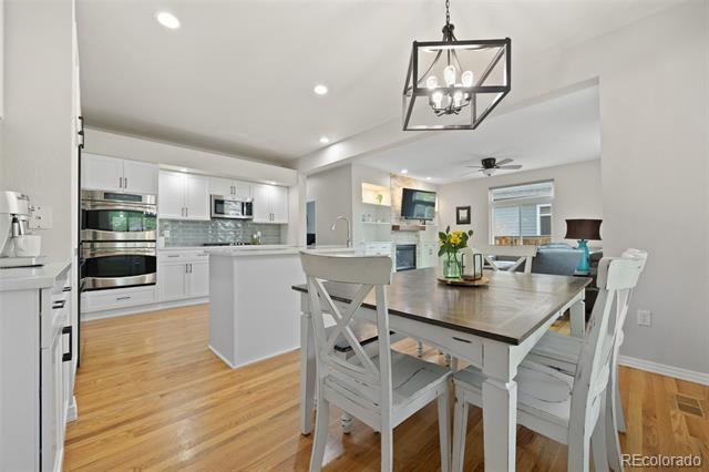 Open kitchen and dining area with white cabinetry, stainless steel appliances, and a large island.