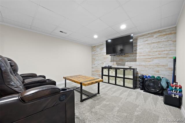 Basement recreation room with leather recliners, wall-mounted TV, and exercise equipment.