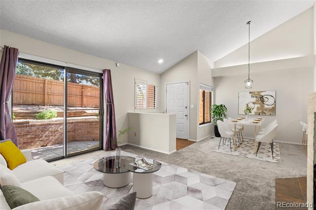Living and dining area with vaulted ceilings, a white sofa, and sliding doors to a fenced patio.