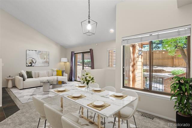 Open dining and living area with a set table, white sectional, and sliding doors to a patio.