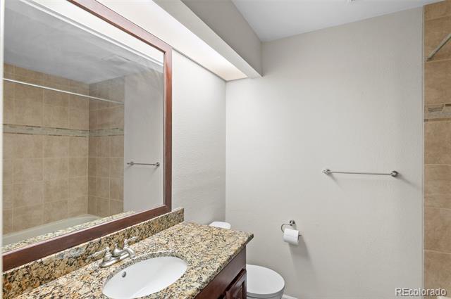 Bathroom with a granite vanity, oval sink, large framed mirror, and toilet.