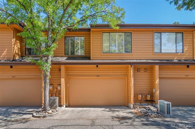 Townhome exterior with unit 424 centered beneath upper windows, partly shaded by a mature tree.