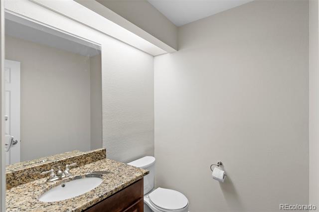 Bathroom with granite vanity, oval sink, large mirror, and toilet.