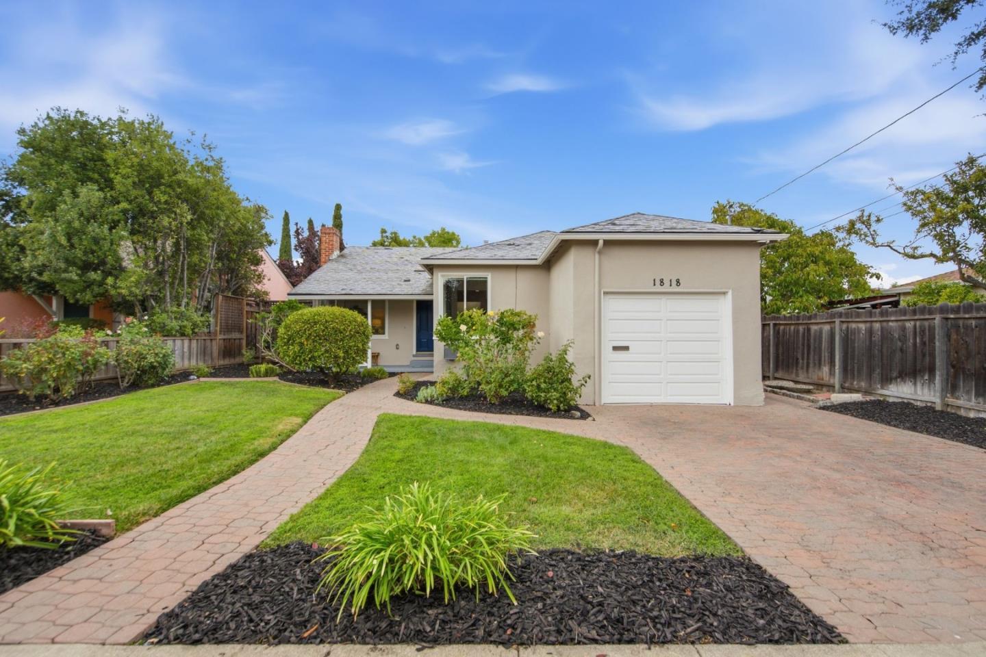 Single-story home with an attached garage, blue front door, and curved brick walkway through the front lawn.