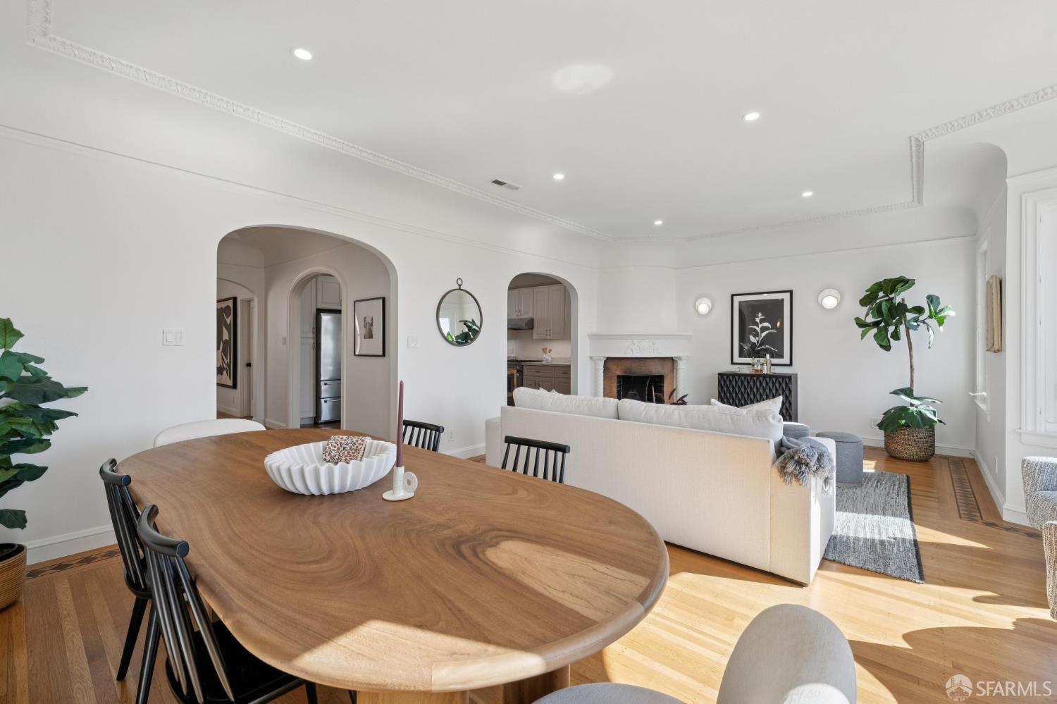 Furnished living and dining room with an oval wood table, arched doorways, and a fireplace.