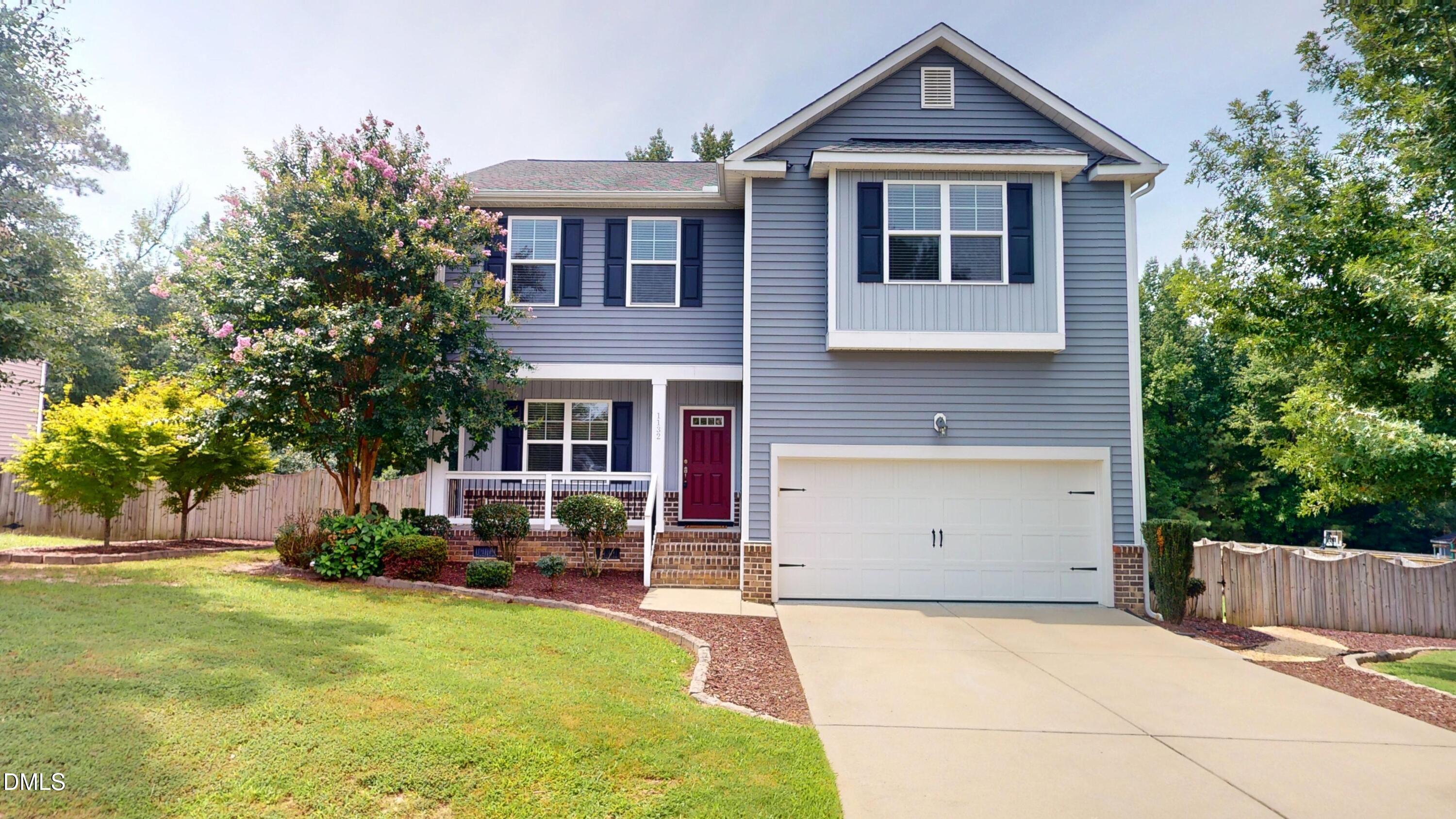 Two-story gray house with navy shutters, a red front door, and an attached two-car garage.