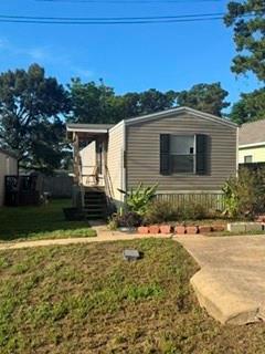 Tan-sided single-story home with a covered entry, front lawn, and concrete driveway.