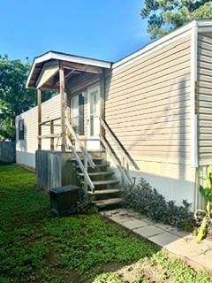 Home exterior with a small raised porch, wooden steps, and a grassy yard.