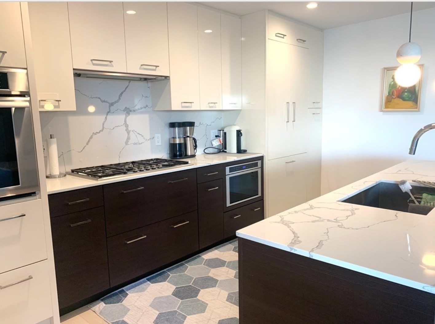 Modern kitchen with marble-look island, gas cooktop, dark cabinets, and geometric tile floor.
