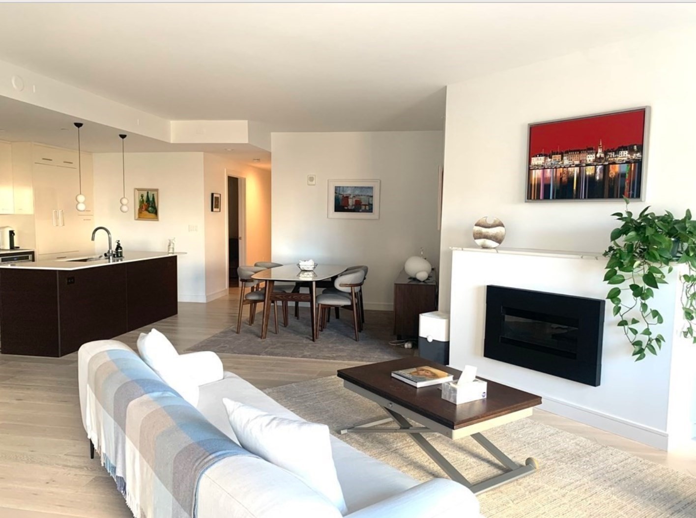 Open-plan living room with a built-in fireplace, sofa, dining area, and kitchen island.