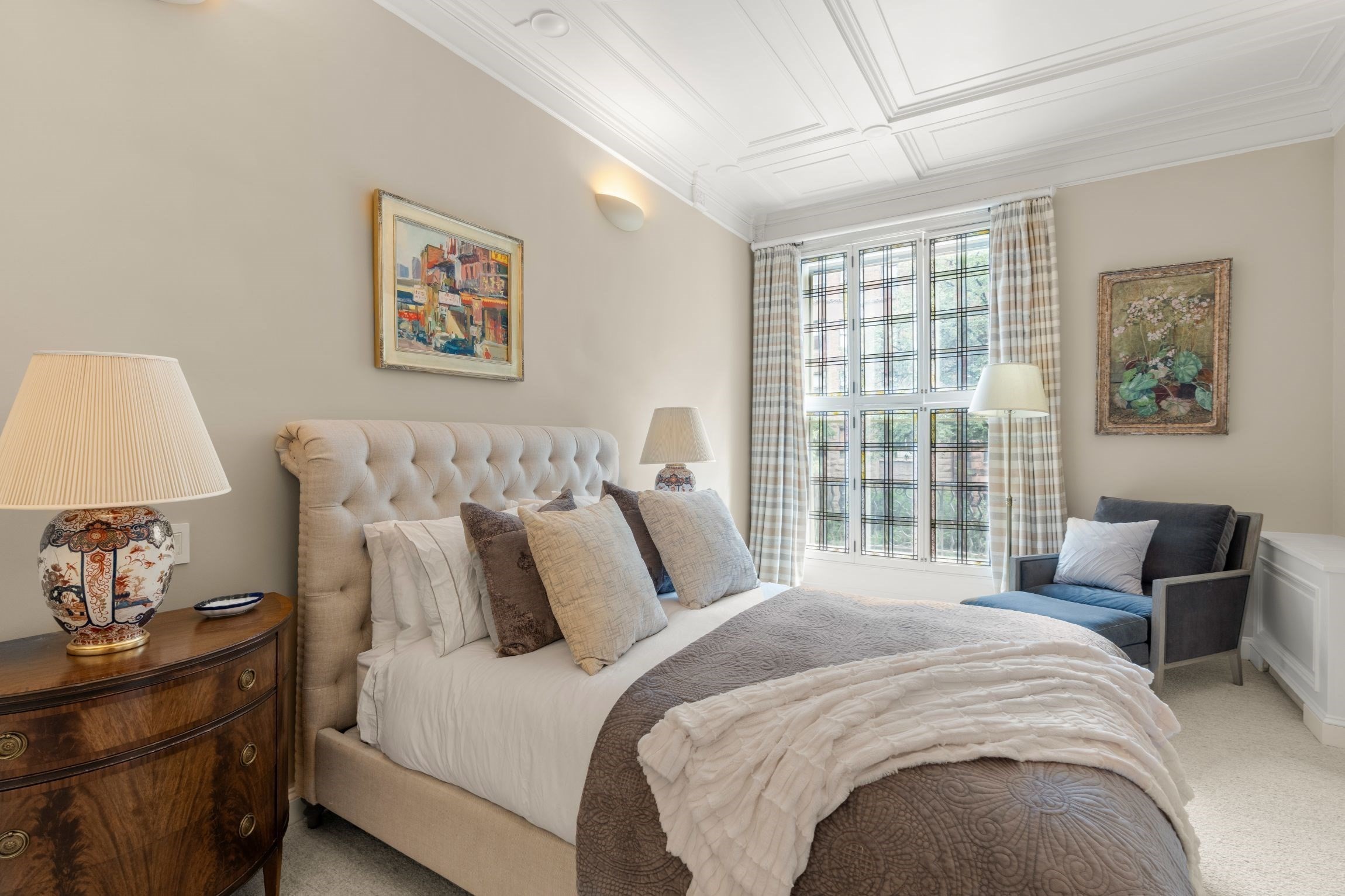 Bedroom with a tufted upholstered bed, tall gridded windows, and a coffered ceiling.