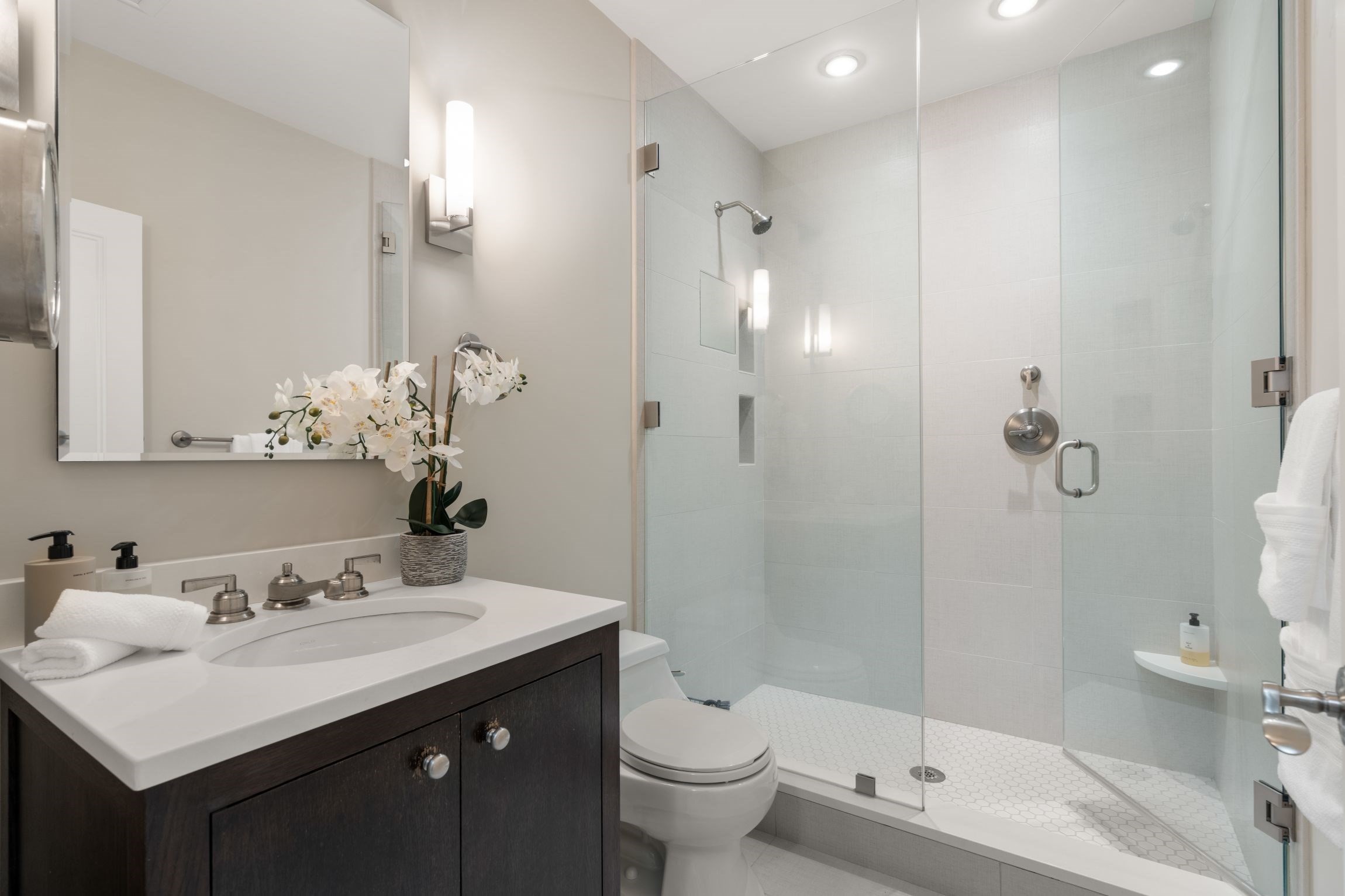 Bathroom with dark wood vanity, white sink, and glass-enclosed shower.