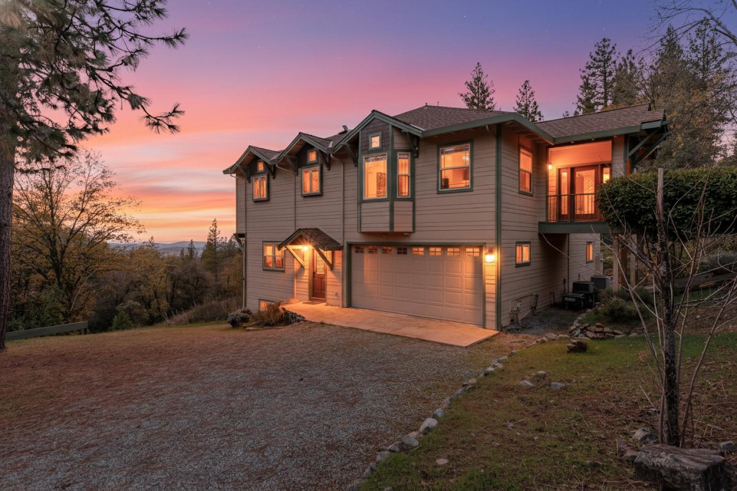 Two-story gray house with a double garage and warmly lit windows at dusk.