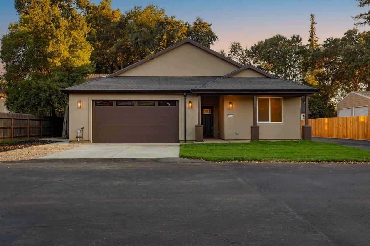 Single-story beige home with a wide garage, concrete driveway, and front lawn at golden hour.