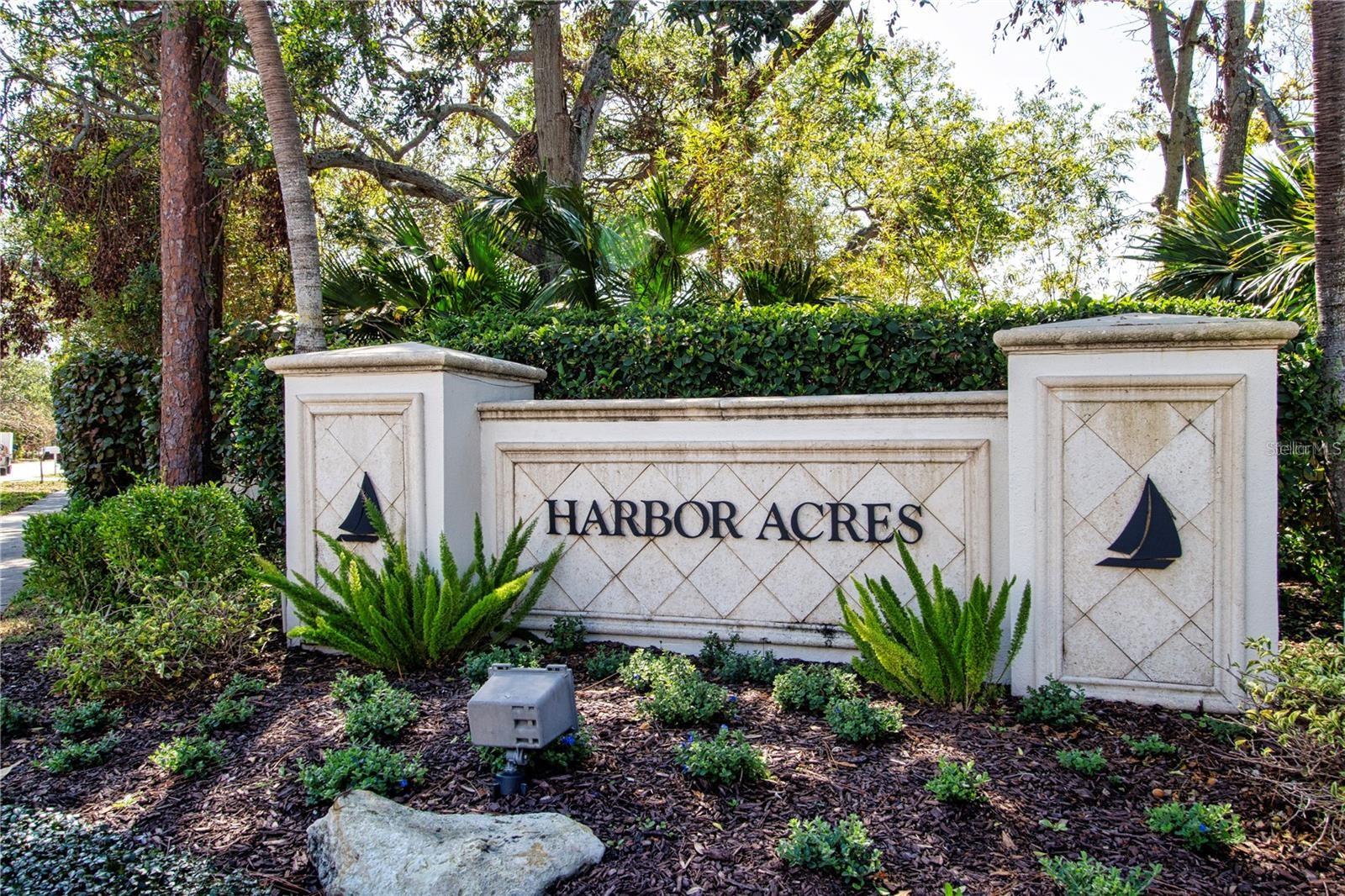 Harbor Acres entrance sign with sailboat emblems and tropical landscaping.