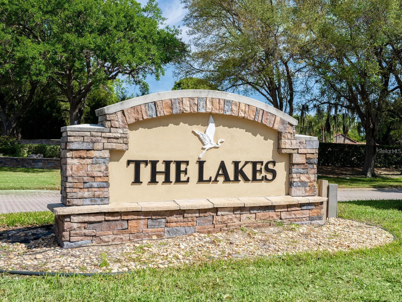 The Lakes community entrance sign with a white bird emblem and stone columns.