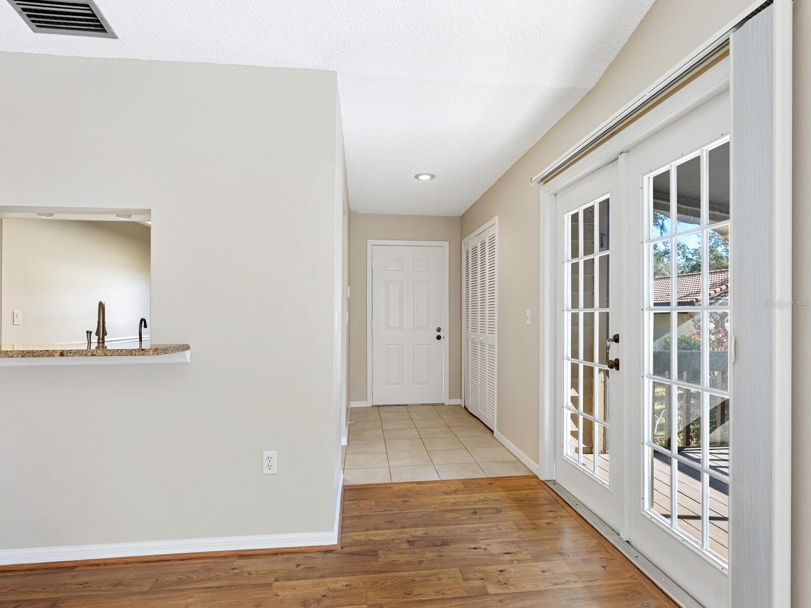 Entry hall with tiled flooring, French doors to a patio, and a pass-through counter.