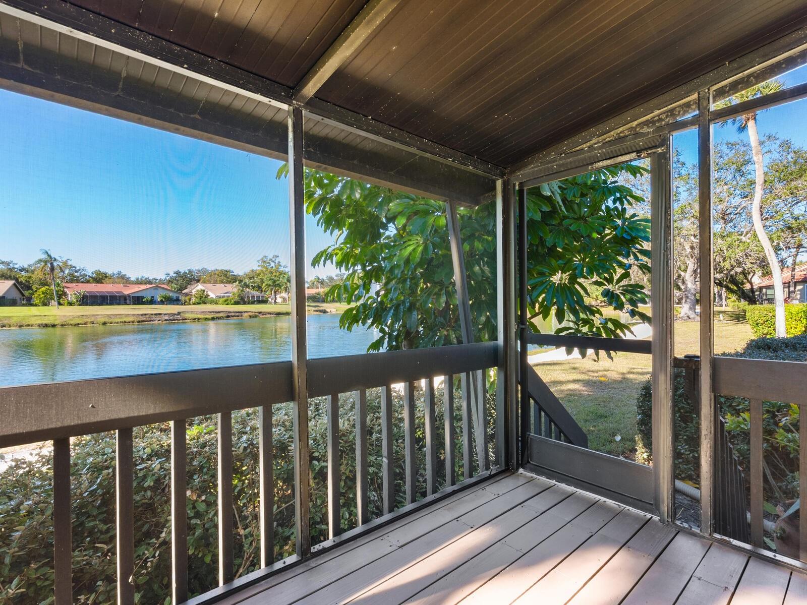 Screened porch overlooking a lake, with dark wood decking and a covered ceiling.
