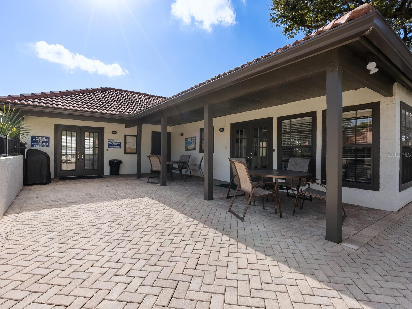 Covered patio with paved flooring and several outdoor tables and chairs.