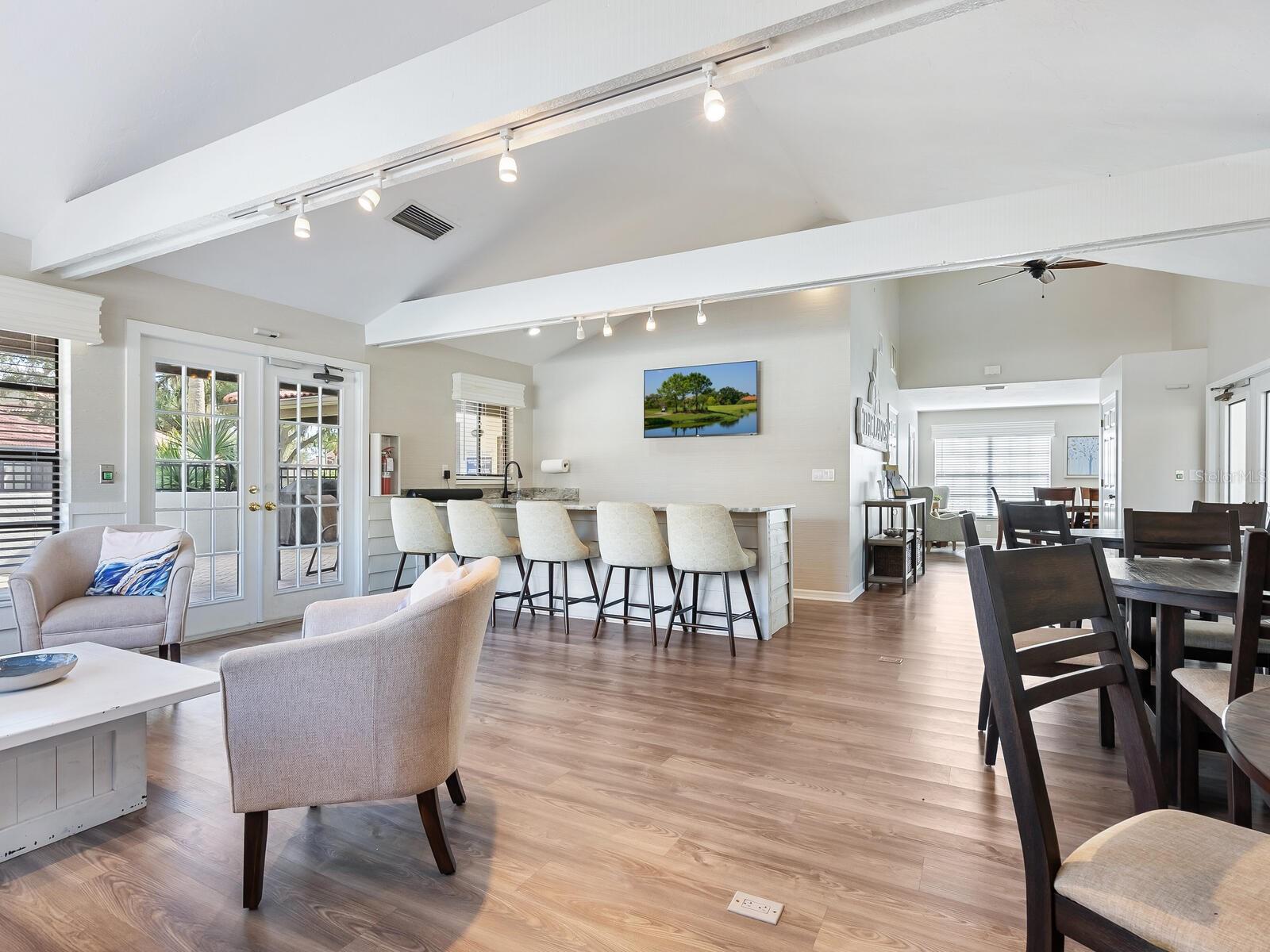 Open-plan living and dining area with vaulted ceiling, kitchen island, and glass patio doors.