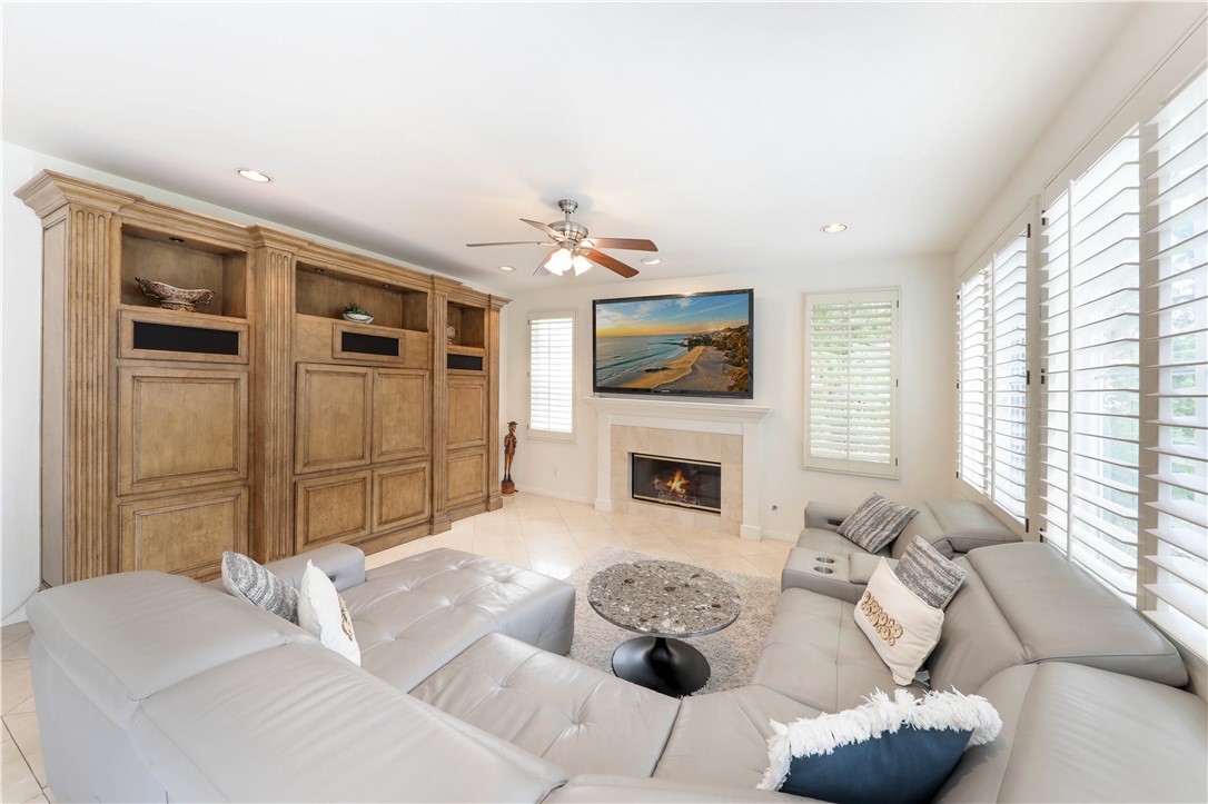 Living room with a gray sectional, built-in wood cabinetry, and a fireplace.