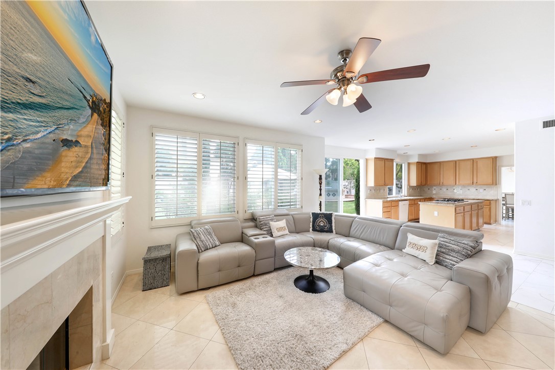 Open-plan living room with a large sectional sofa, fireplace, and adjoining wood-cabinet kitchen.