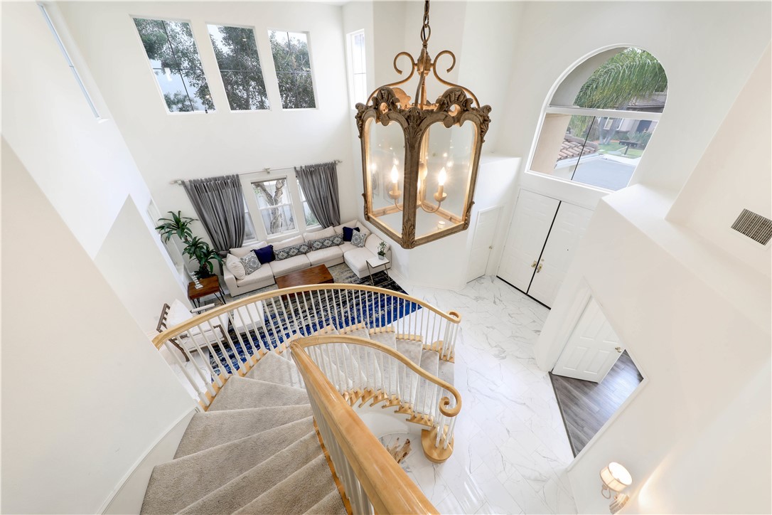 Two-story foyer with a curved staircase, ornate chandelier, and living room below.