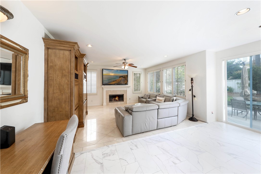 Furnished living room with a white sectional, fireplace, wood cabinetry, and sliding glass doors to a patio.