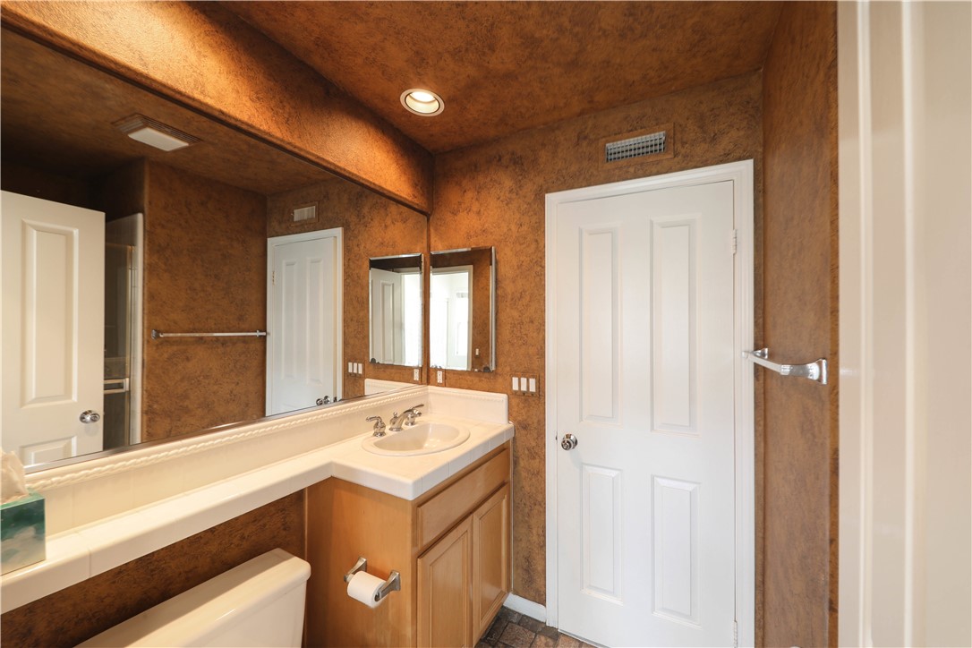 Bathroom with a long mirrored countertop, built-in sink, and wood vanity.