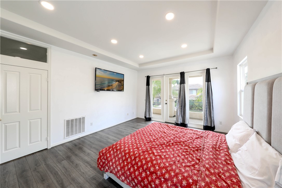 Bedroom with a red patterned bedspread and glass doors opening to a balcony.