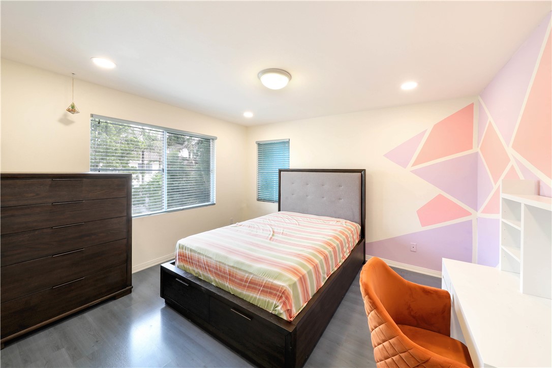 Bedroom with dark wood furniture, striped bedding, and a colorful geometric wall mural.