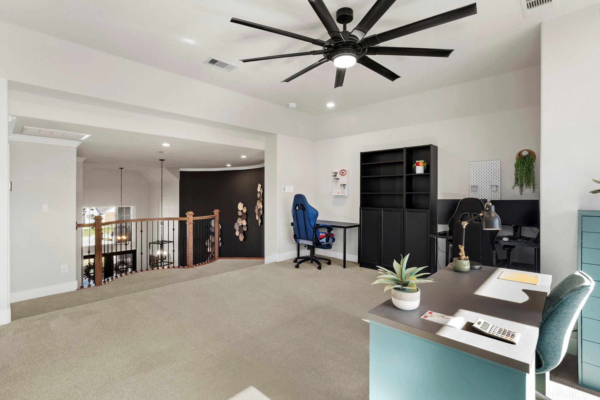 Furnished upper-level home office with two workstations and a railing overlooking the floor below.