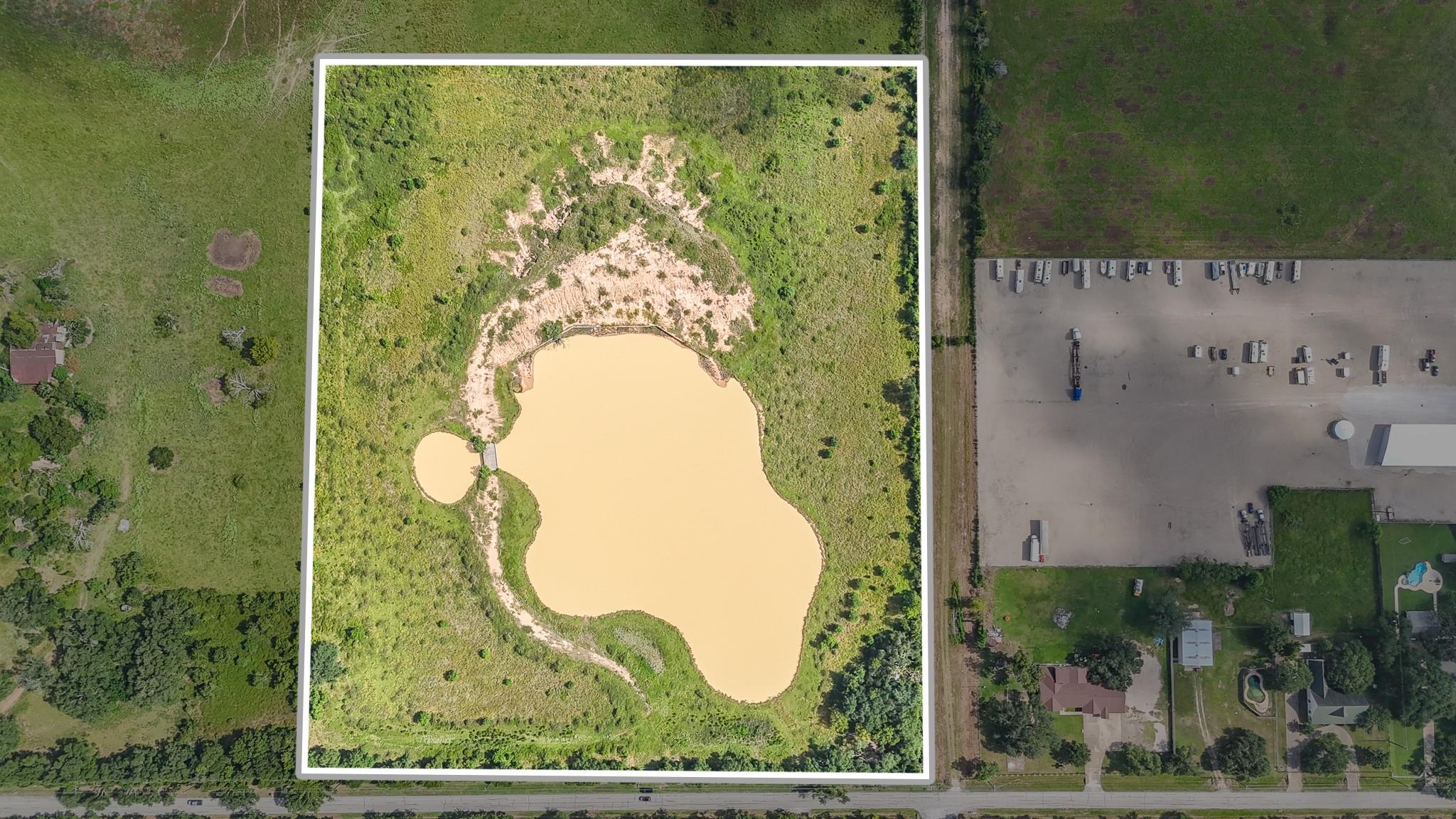 Aerial view of a green parcel outlined in white, with a large pond.