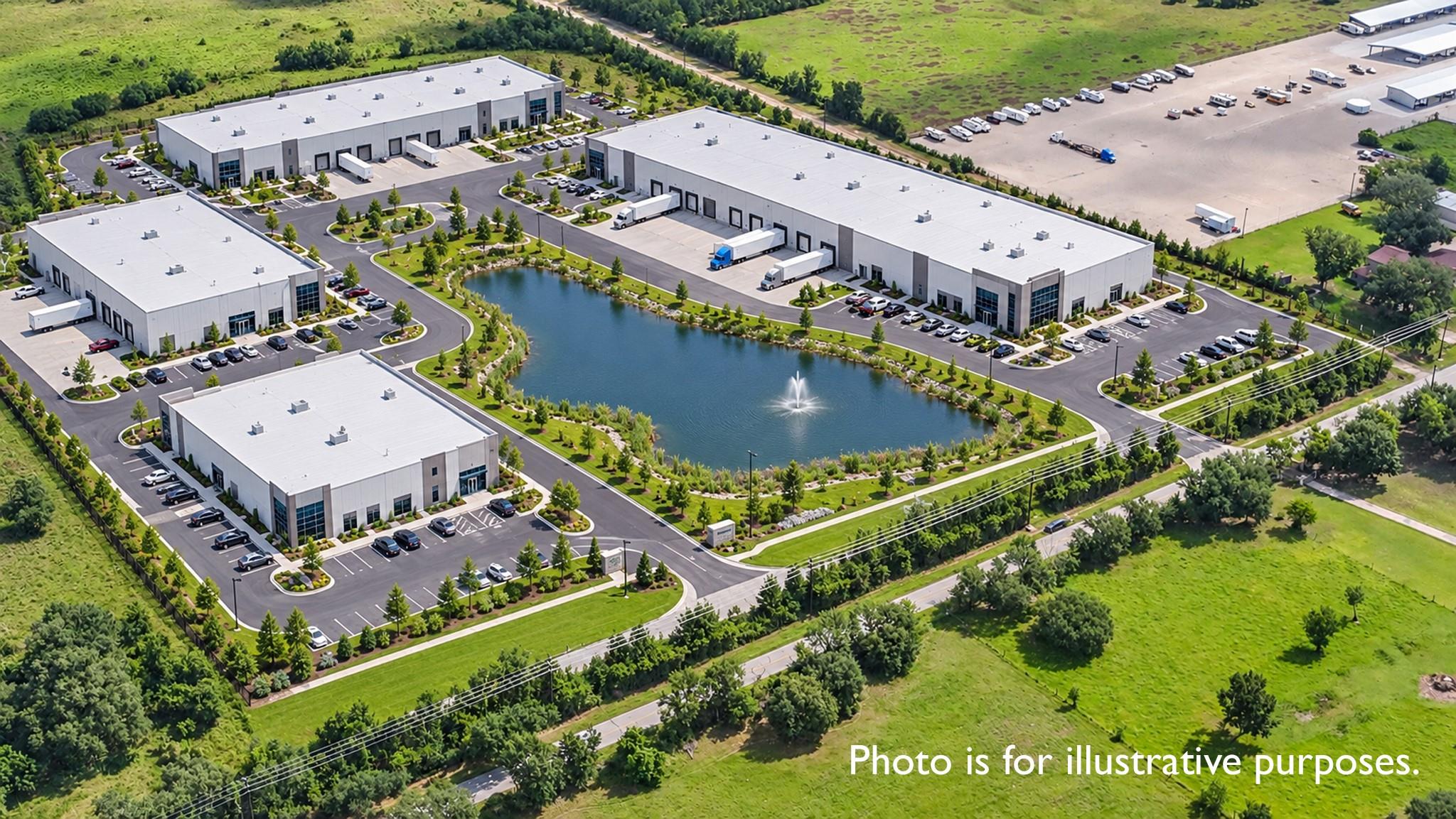 Aerial view of white-roofed warehouses surrounding a landscaped pond with a fountain.