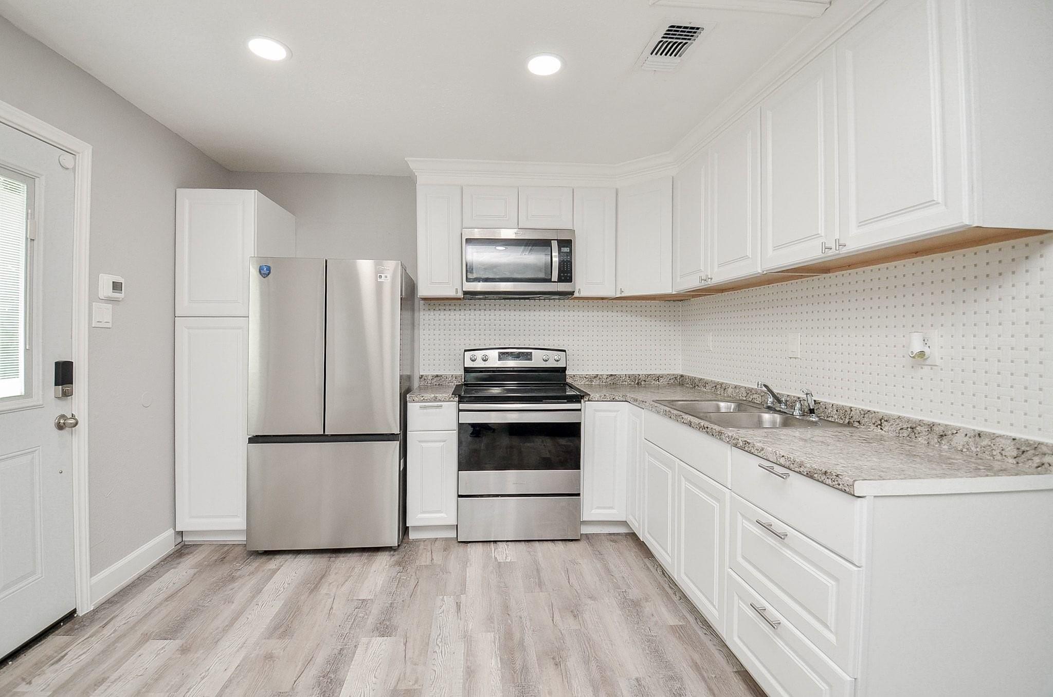 Kitchen with white cabinets, stainless steel appliances, and a double-basin sink.