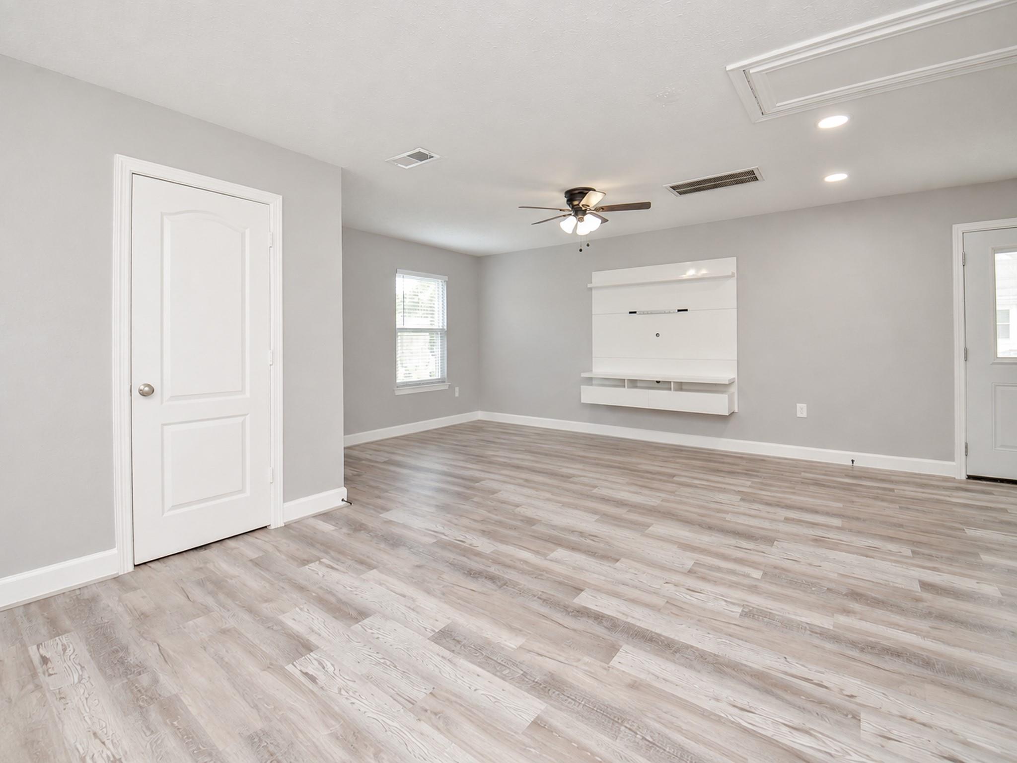 Vacant living room with a white built-in media center and light wood-look flooring.