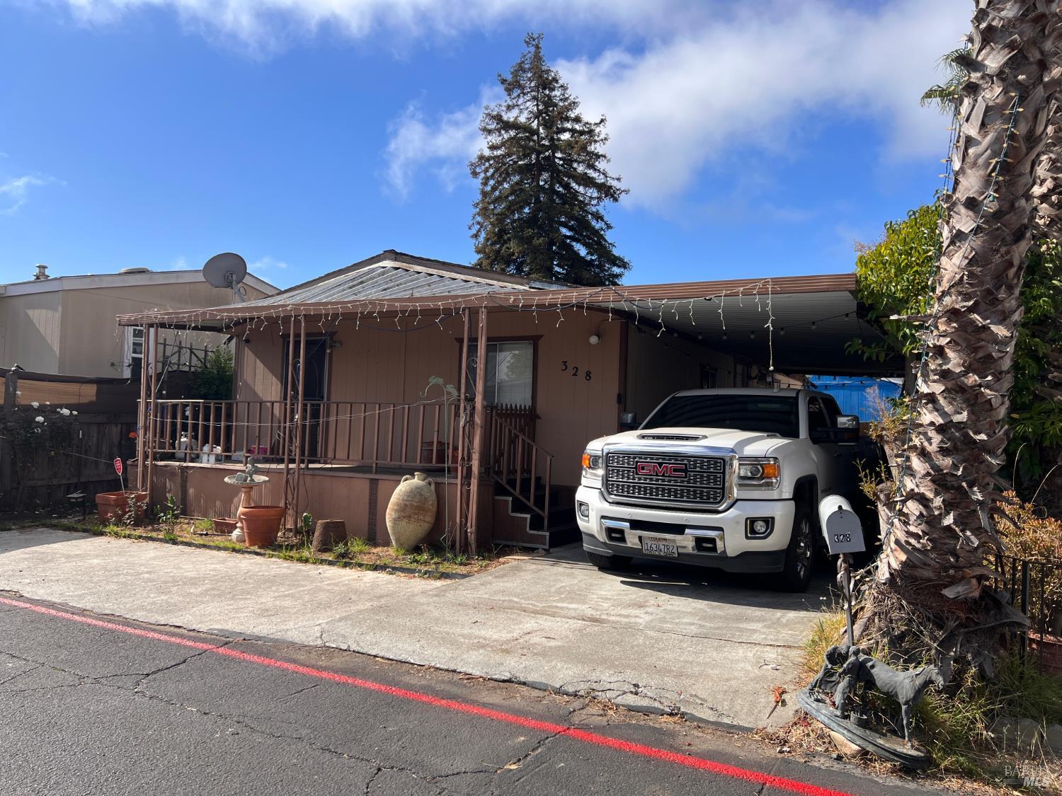 Single-story brown home with a covered porch, carport, and white GMC pickup.