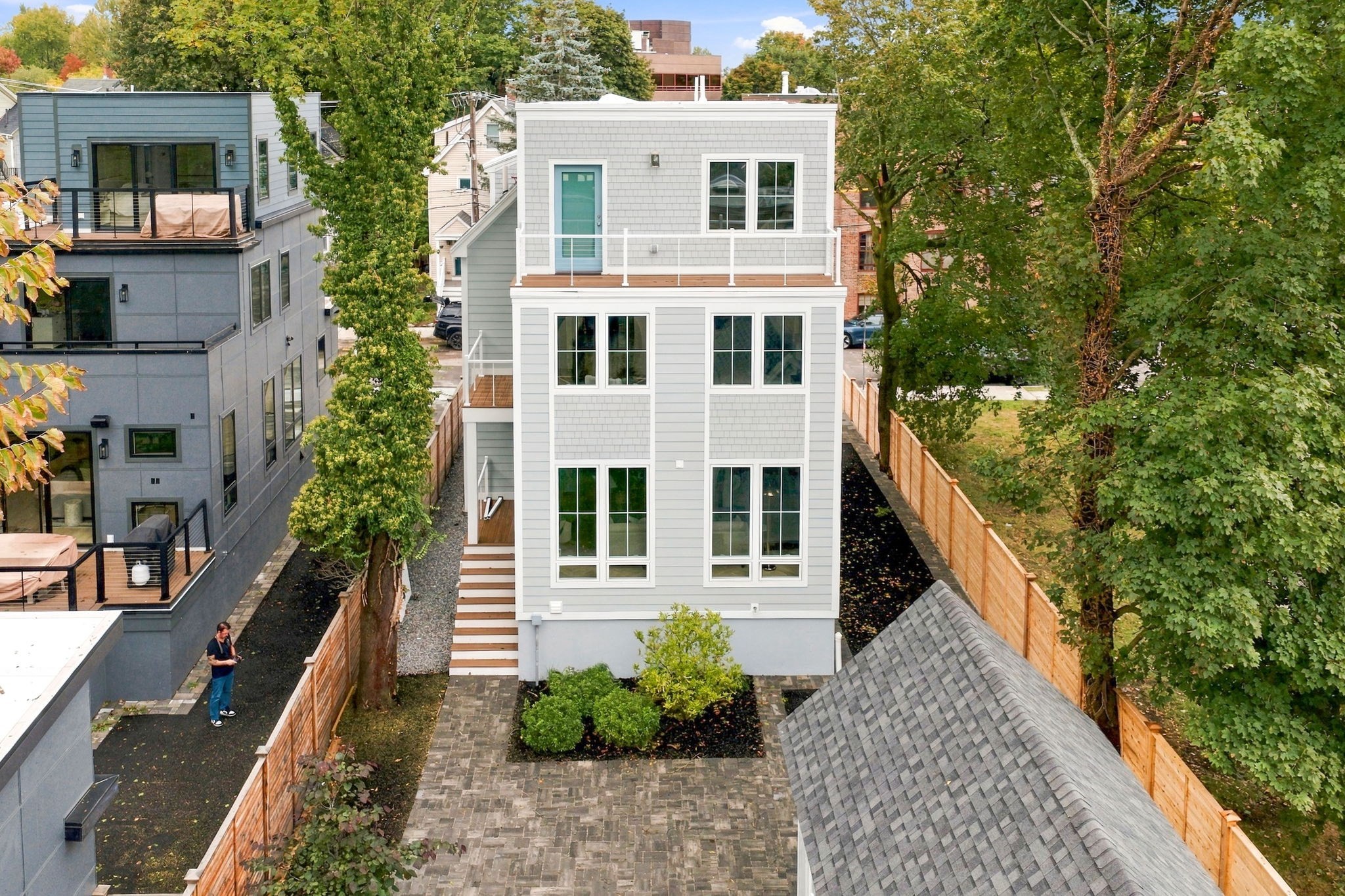 Modern gray house with a second-floor balcony, fenced patio, and landscaped garden.