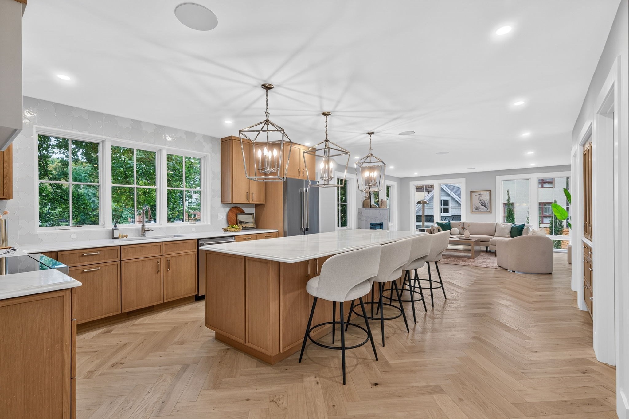 Open-plan kitchen with a large island and wood cabinetry flowing into a bright living room.