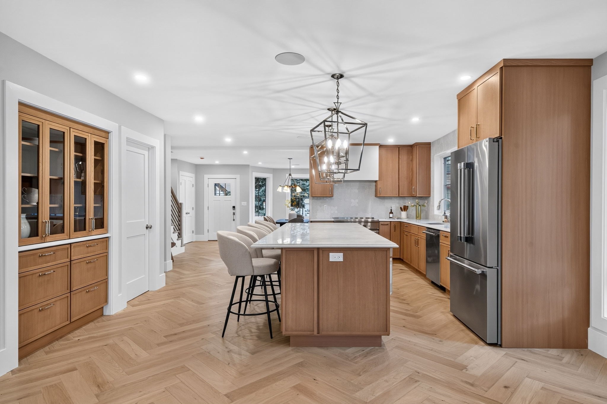 Kitchen with a large wood island, stone countertop, upholstered stools, and stainless steel appliances.