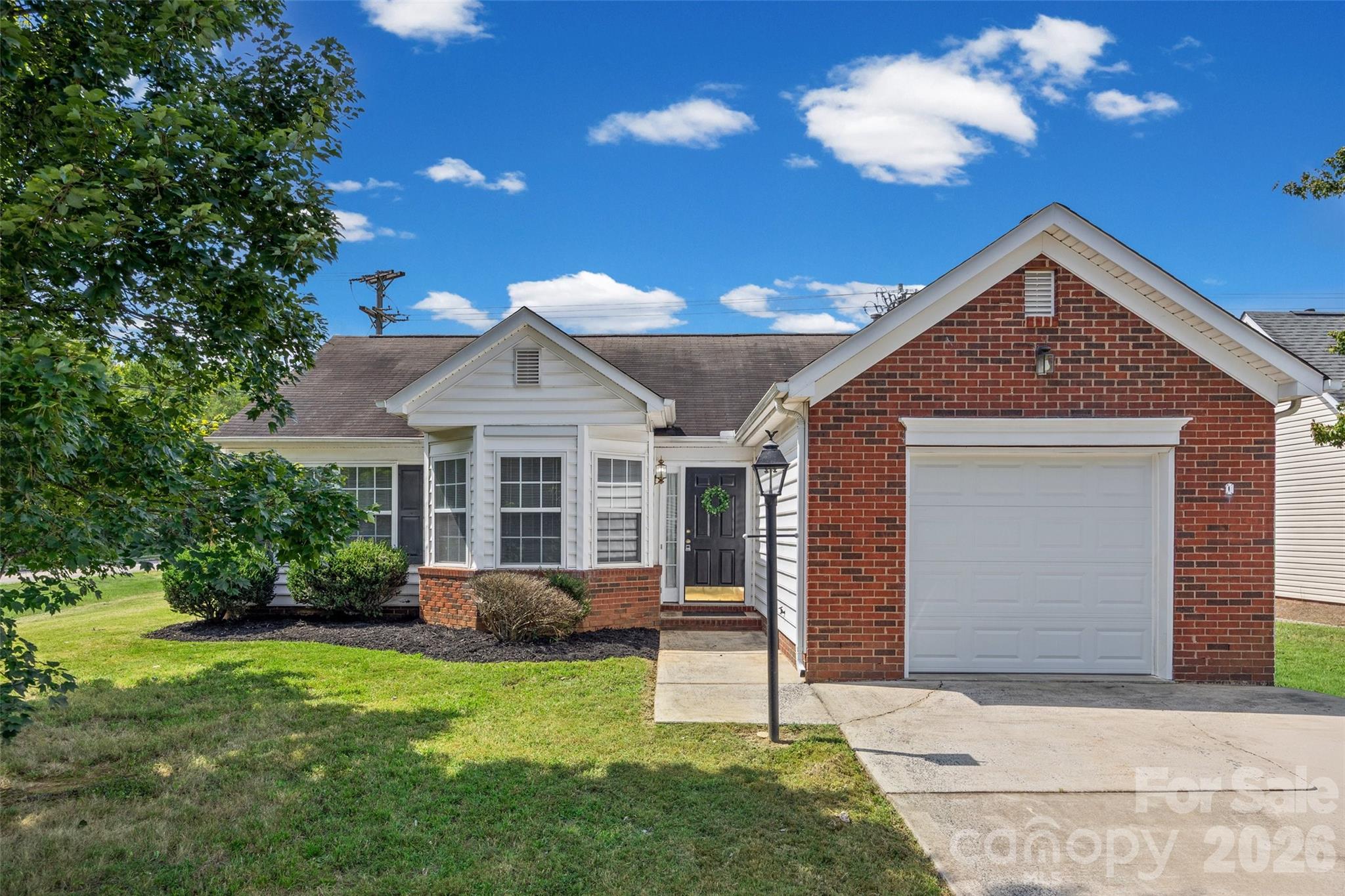 Single-story brick-and-siding home with an attached garage, bay windows, and a front lawn.