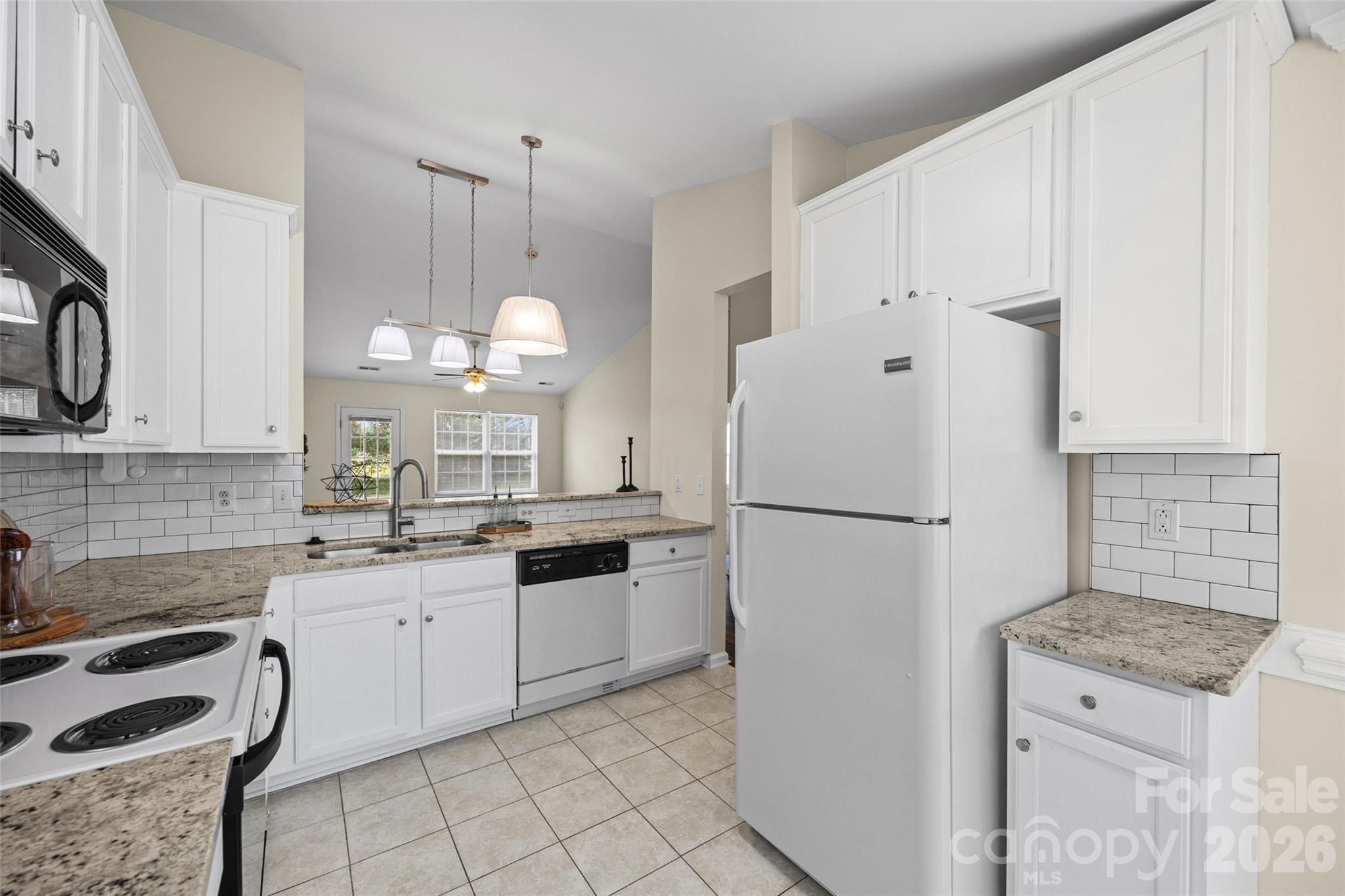 Kitchen with white cabinets, granite counters, subway tile backsplash, and white appliances.