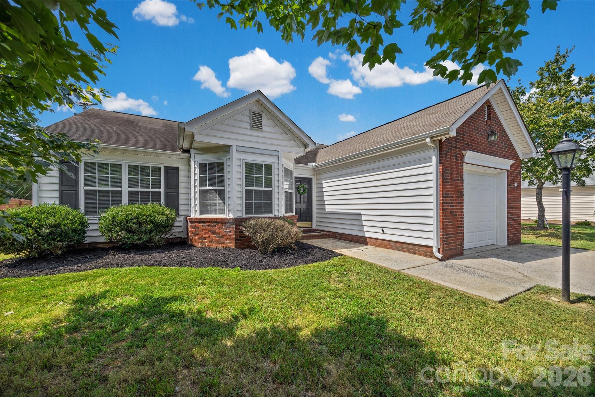 Home exterior with white siding, brick accents, bay window, and attached garage.