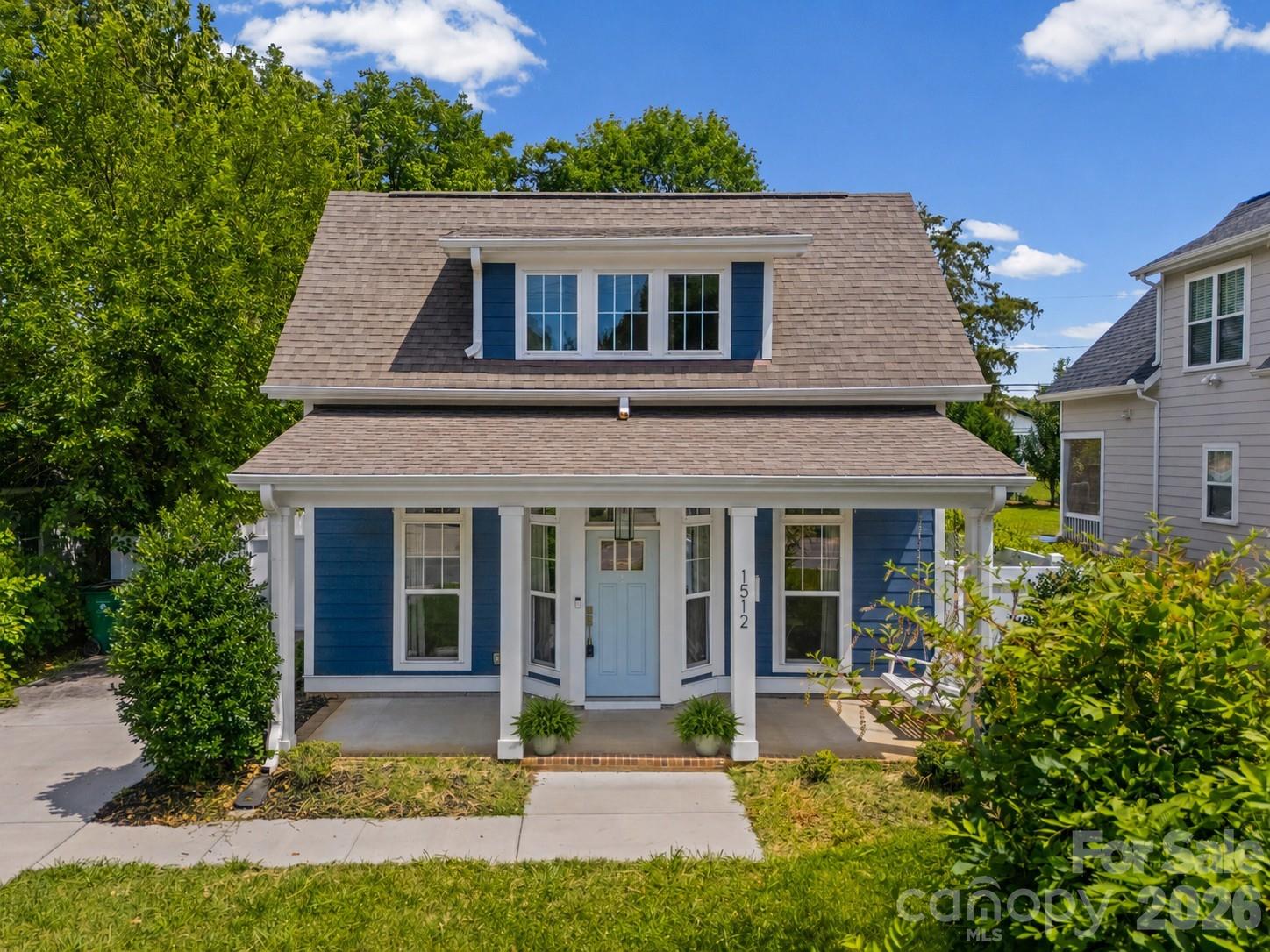 Blue house with white trim, covered front porch, and three-window dormer; number 1512 beside the door.