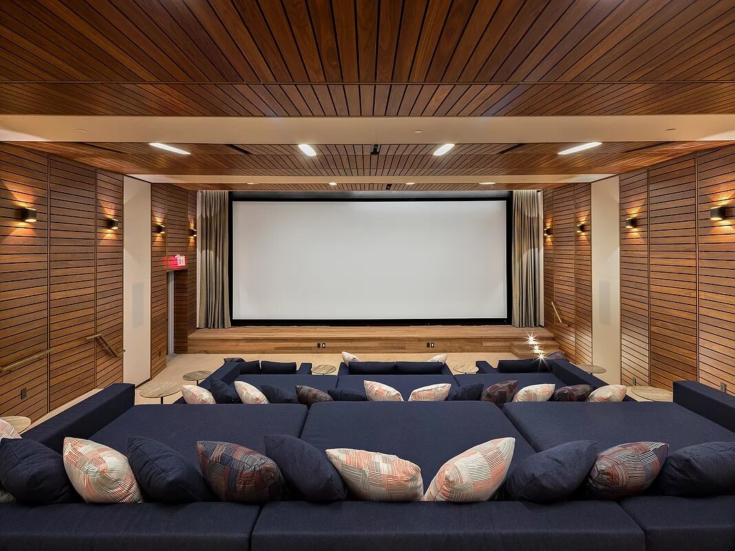 Screening room with navy sofas, a large projection screen, and wood-paneled walls and ceiling.